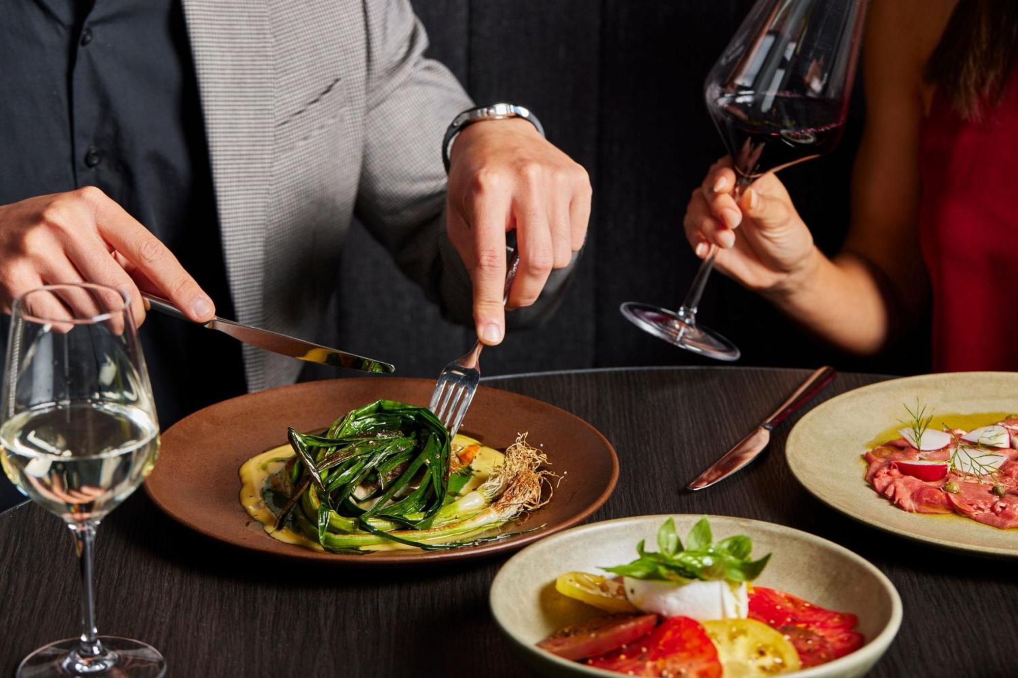 Melbourne Marriott Hotel Docklands Kültér fotó A man using a knife and fork to cut into a meal